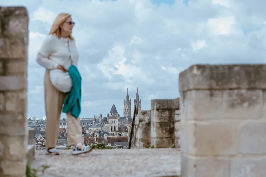 Femme marchant sur les remparts du château de Caen avec, en fond, une vue d'ensemble sur Caen