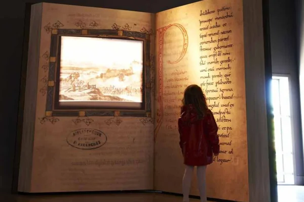 Petite fille devant un manuscrit monumental au Scriptorial d'Avranches